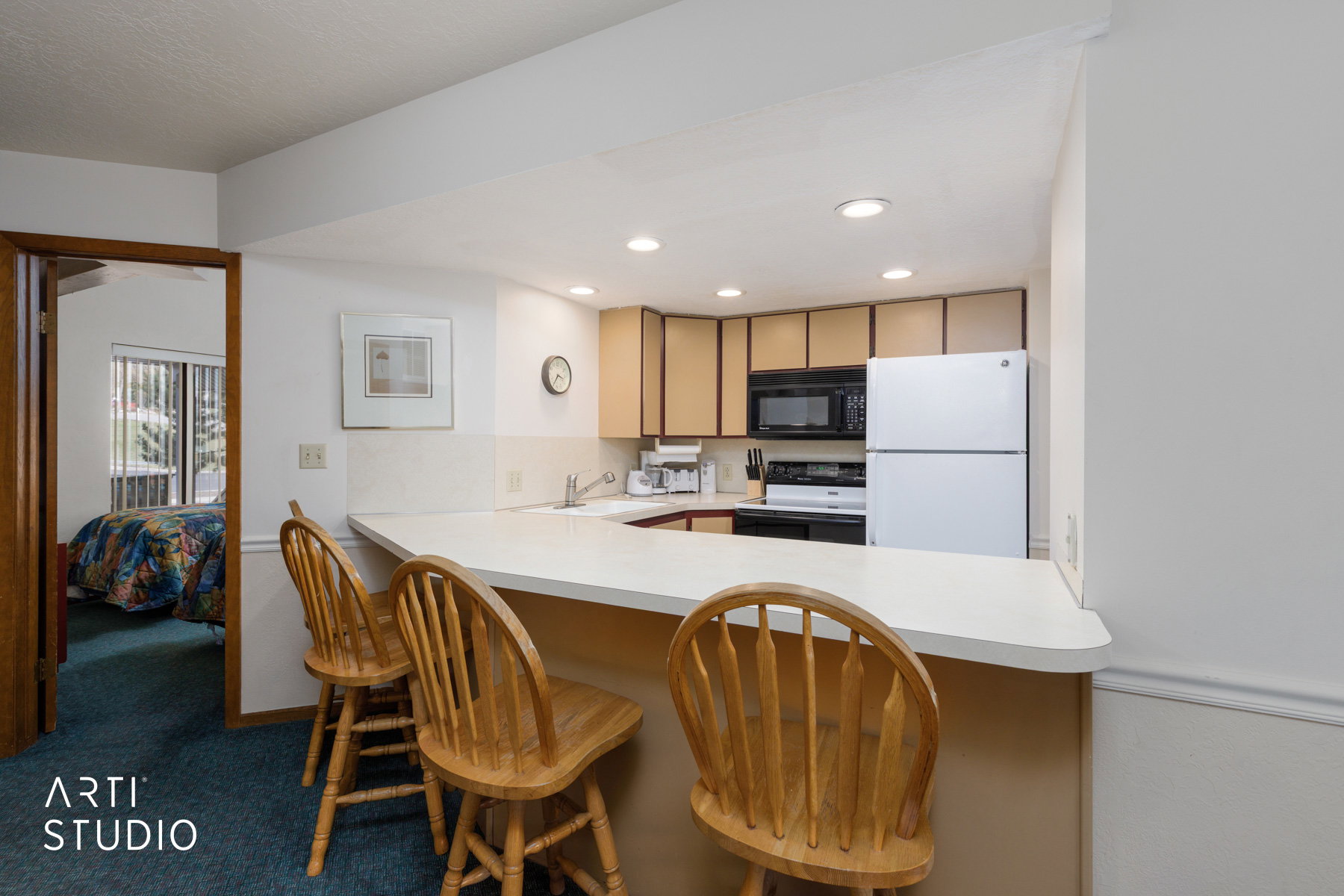 Kitchen featuring a breakfast bar with seating, wood-finish cabinetry, white appliances, and a white countertop