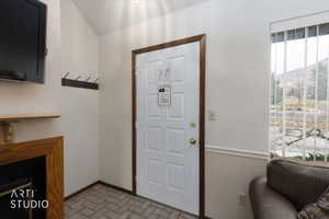 Entryway featuring a paneled door with wood-finish trim, herringbone tile flooring, and a window with vertical blinds