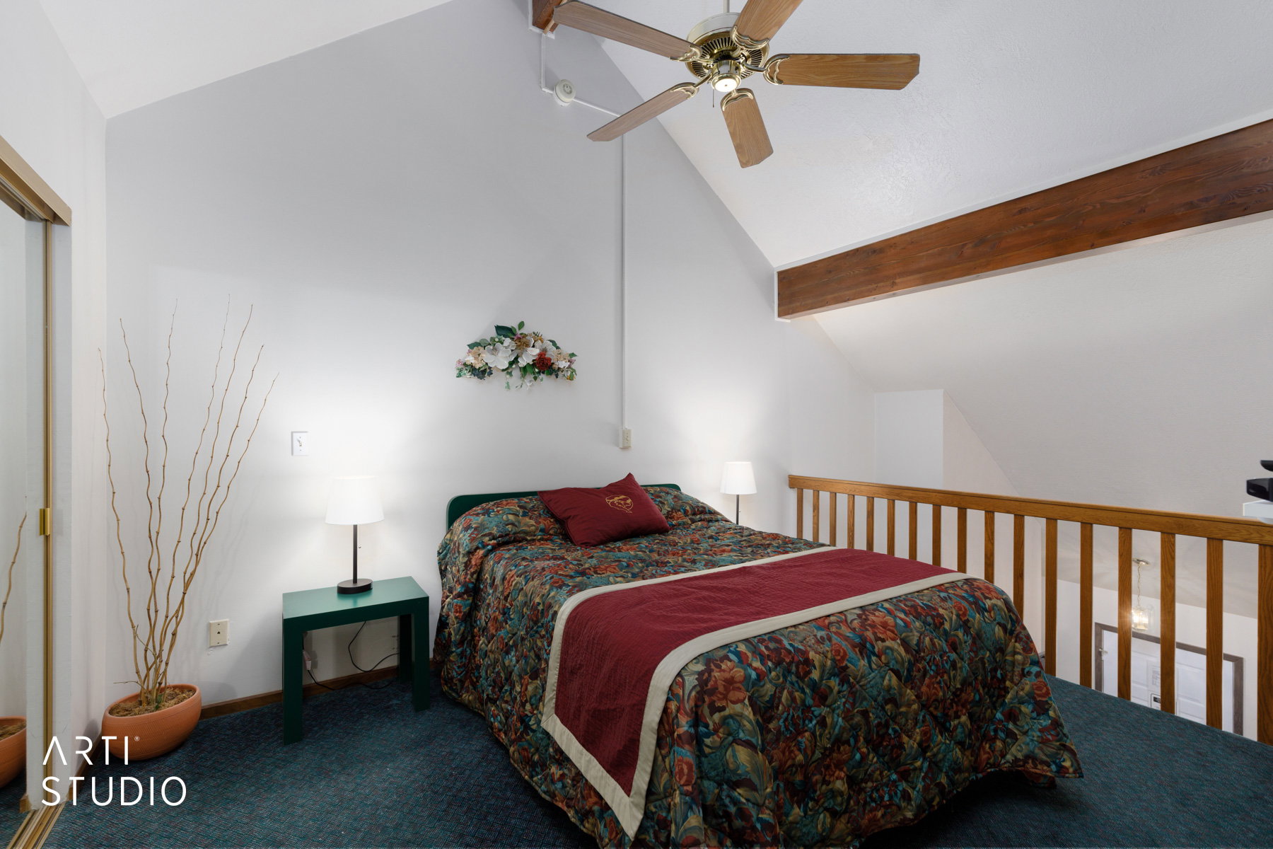 Vaulted ceiling loft bedroom featuring a ceiling fan, exposed wood beam, wood-finish railing, and wall-to-wall carpeting