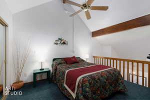 Vaulted ceiling loft bedroom featuring a ceiling fan, exposed wood beam, wood-finish railing, and wall-to-wall carpeting