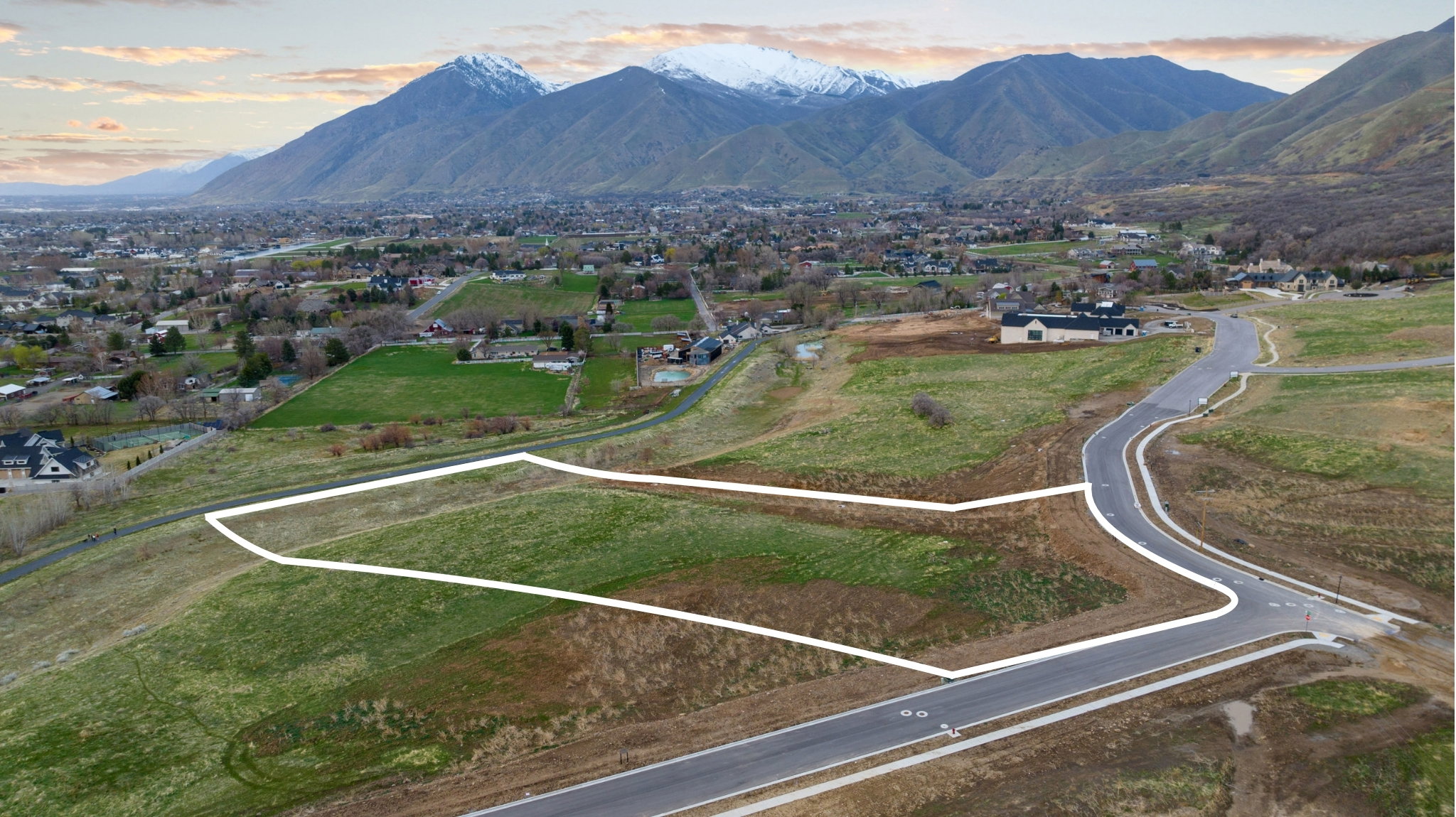 Expansive parcel featuring a paved street, curb, and a natural, gently sloping terrain
