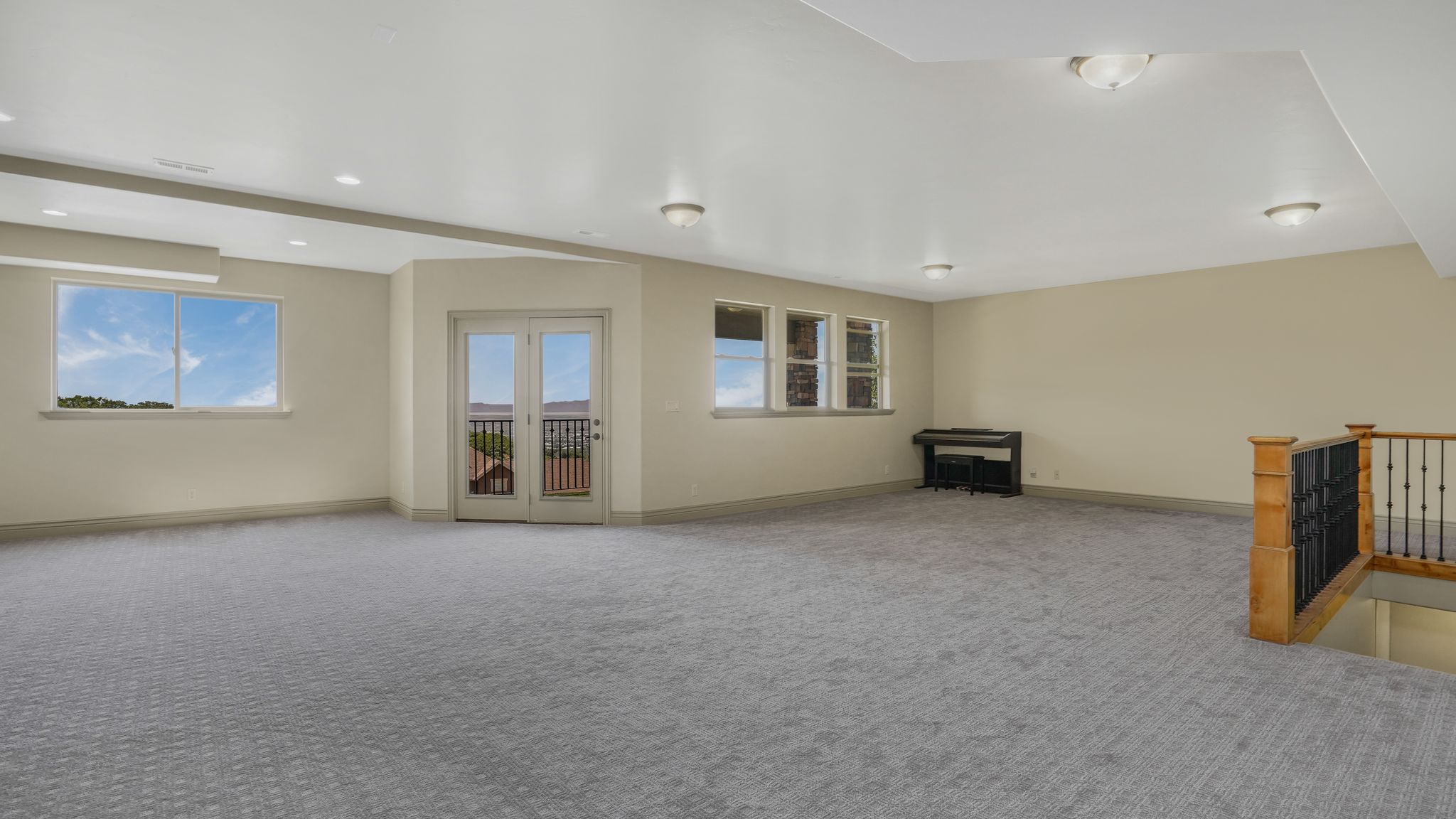 Spacious room featuring patterned gray carpeting, light-toned walls, and recessed lighting