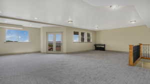 Spacious room featuring patterned gray carpeting, light-toned walls, and recessed lighting