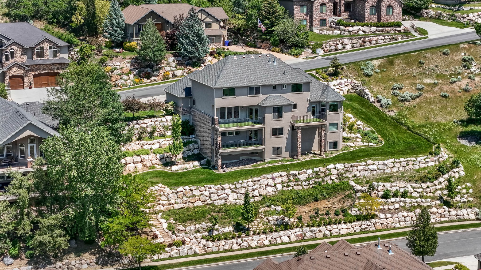 Multi-level residence featuring a gray shingle roof and a stucco exterior with stone accents