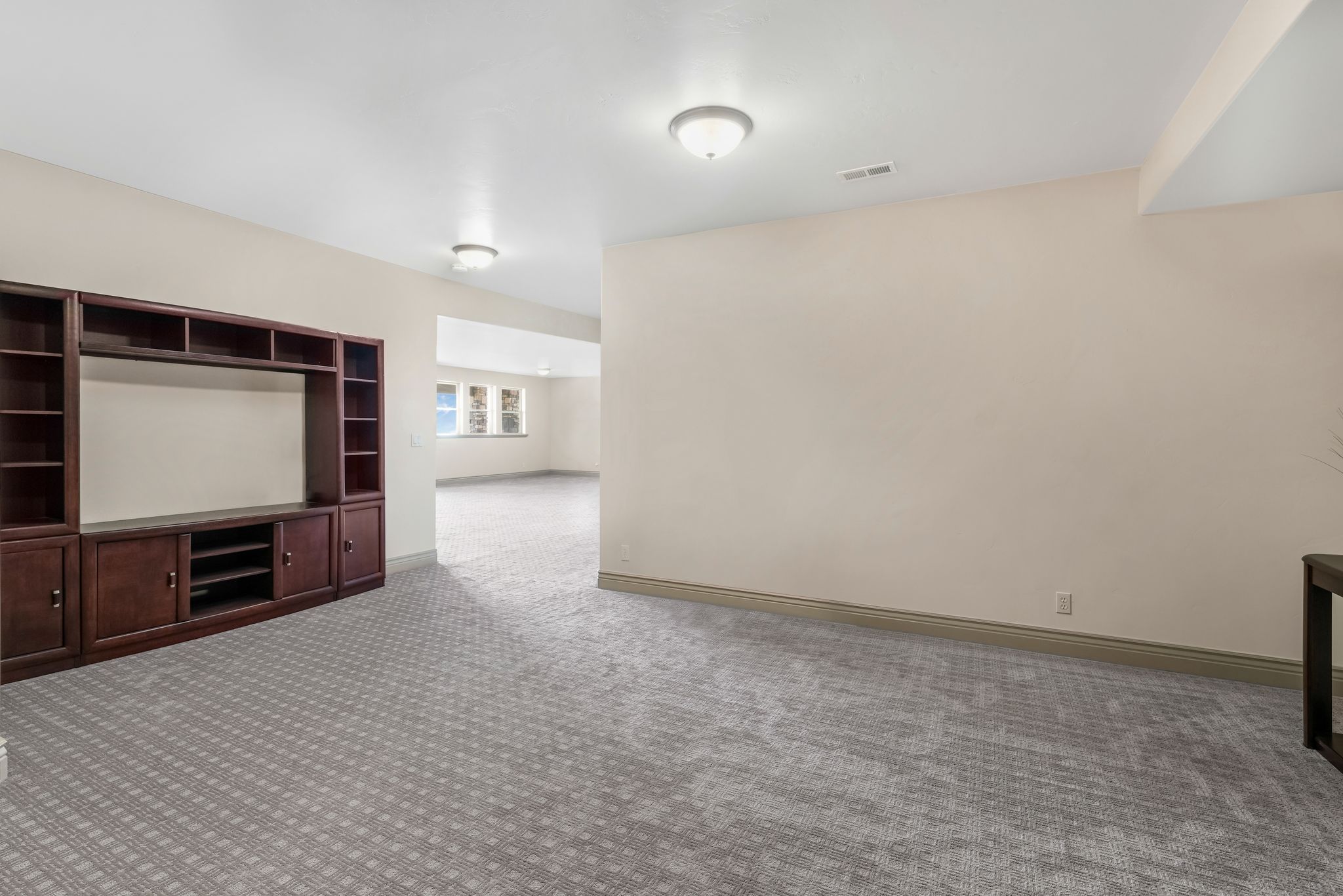 Spacious room with patterned carpet flooring, recessed lighting, and a built-in media center