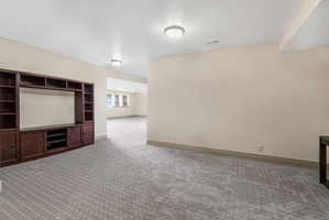 Spacious room with patterned carpet flooring, recessed lighting, and a built-in media center