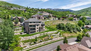Multi-story residence featuring a tiered landscape design with stone retaining walls