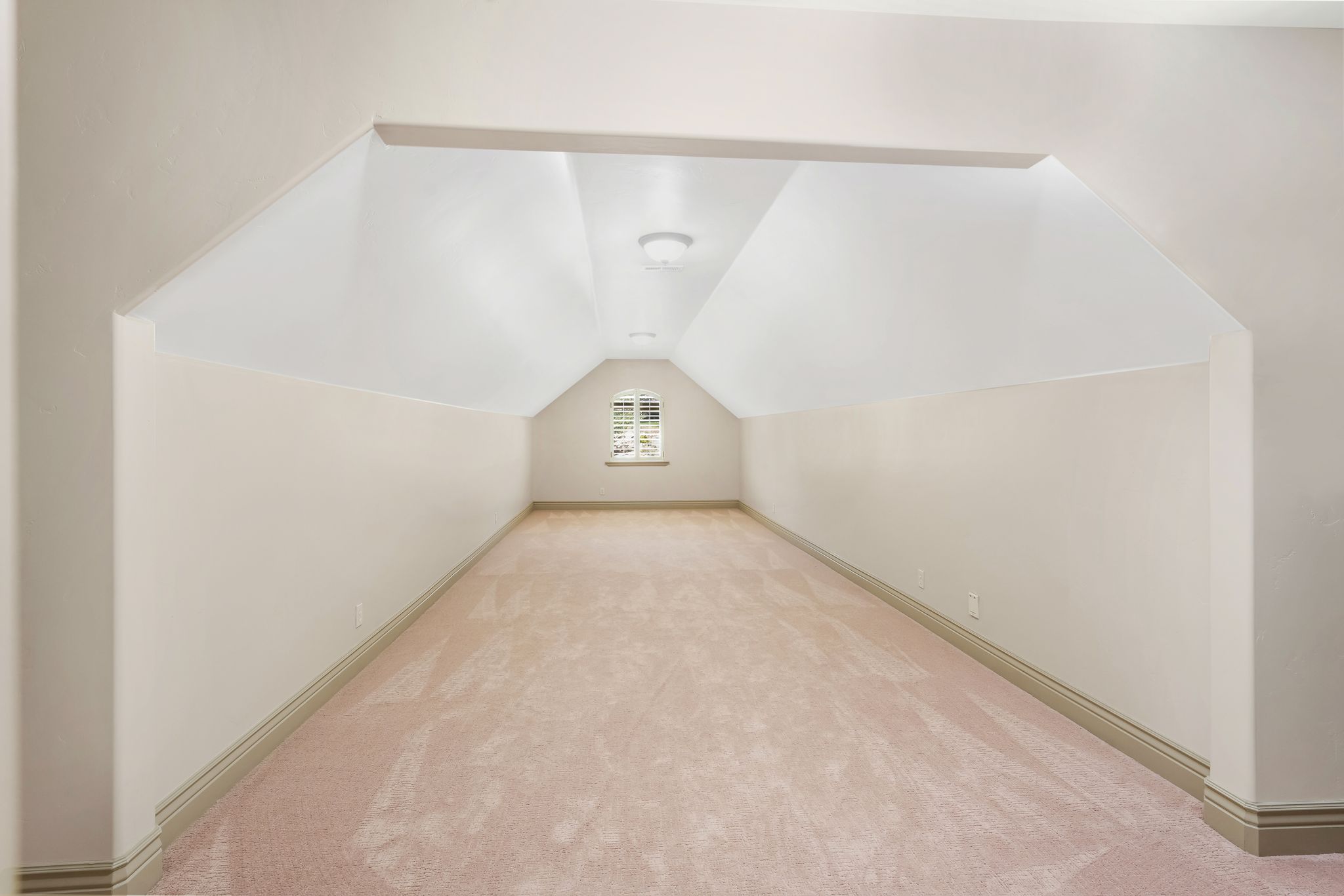 Expansive carpeted room featuring sloped ceilings, a window with muntins, and recessed lighting