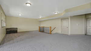 Spacious room featuring patterned gray carpeting, light beige walls, and multiple flush-mount ceiling lights