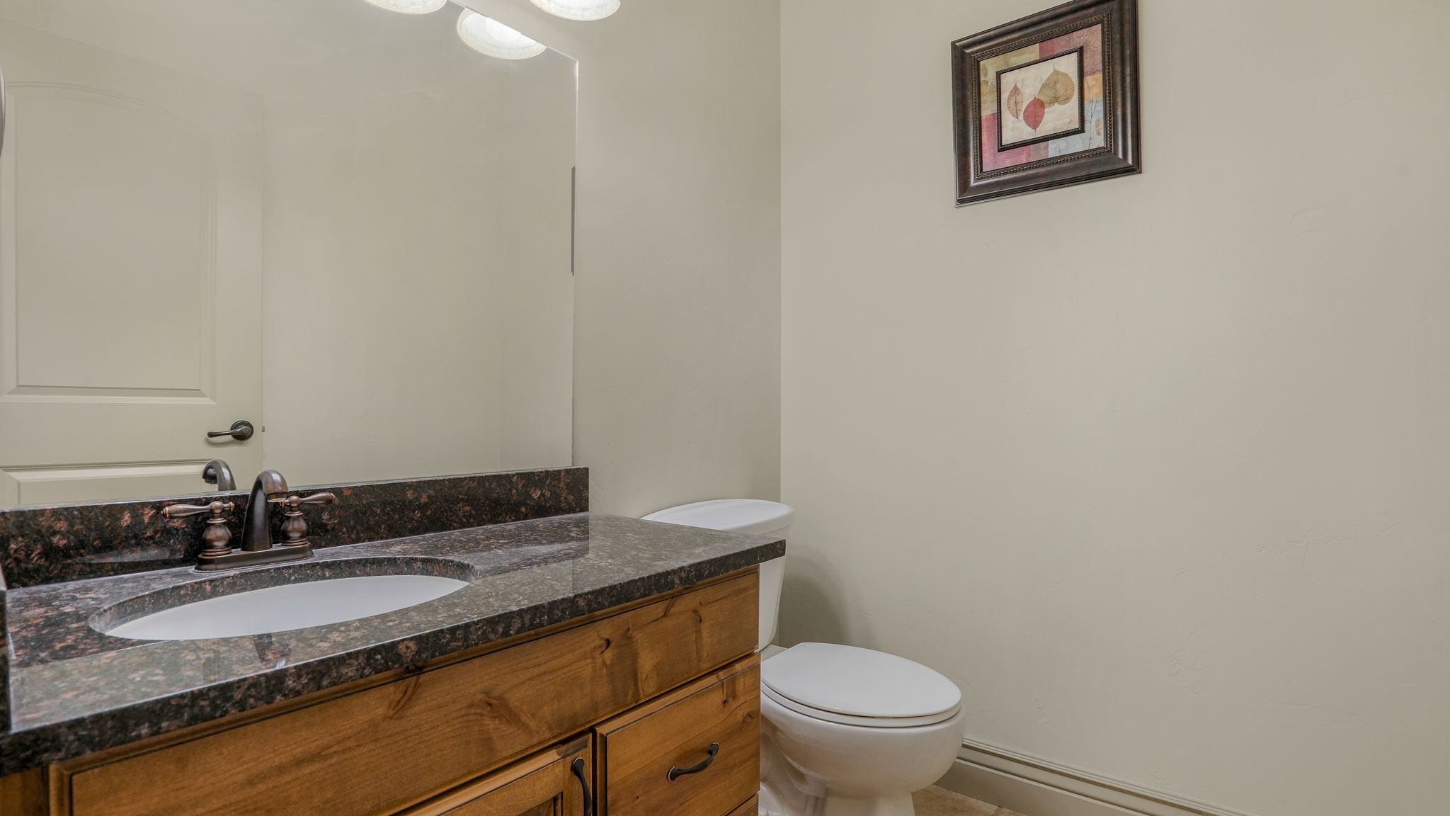 Bathroom vanity featuring a granite countertop, undermount sink, and bronze-finish faucet