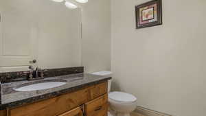 Bathroom vanity featuring a granite countertop, undermount sink, and bronze-finish faucet