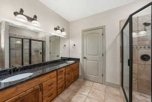 Dual vanity with a black stone countertop, integrated sinks, and bronze-finish fixtures