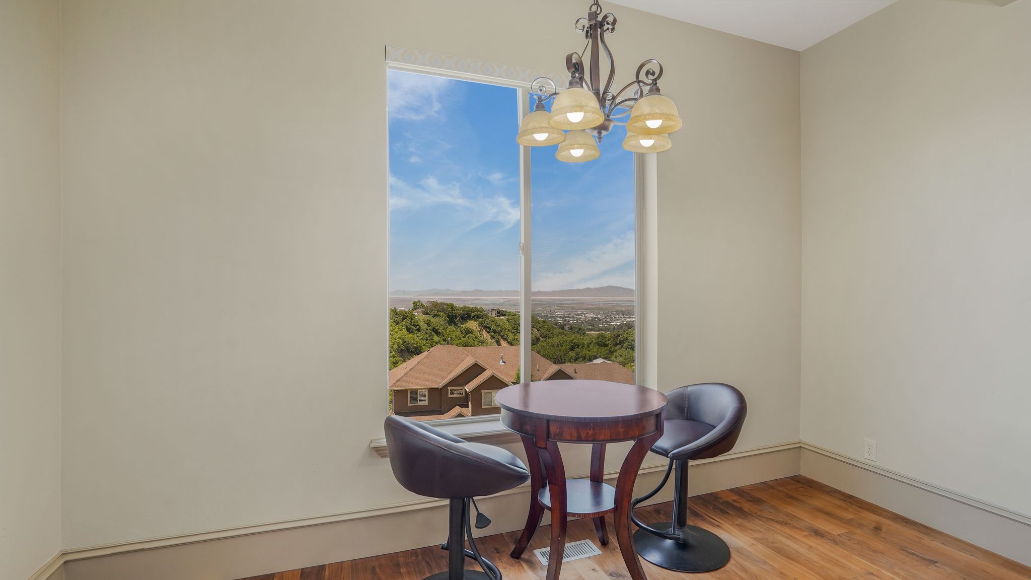 Tall window framing a distant landscape, featuring a decorative chandelier with multiple glass shades