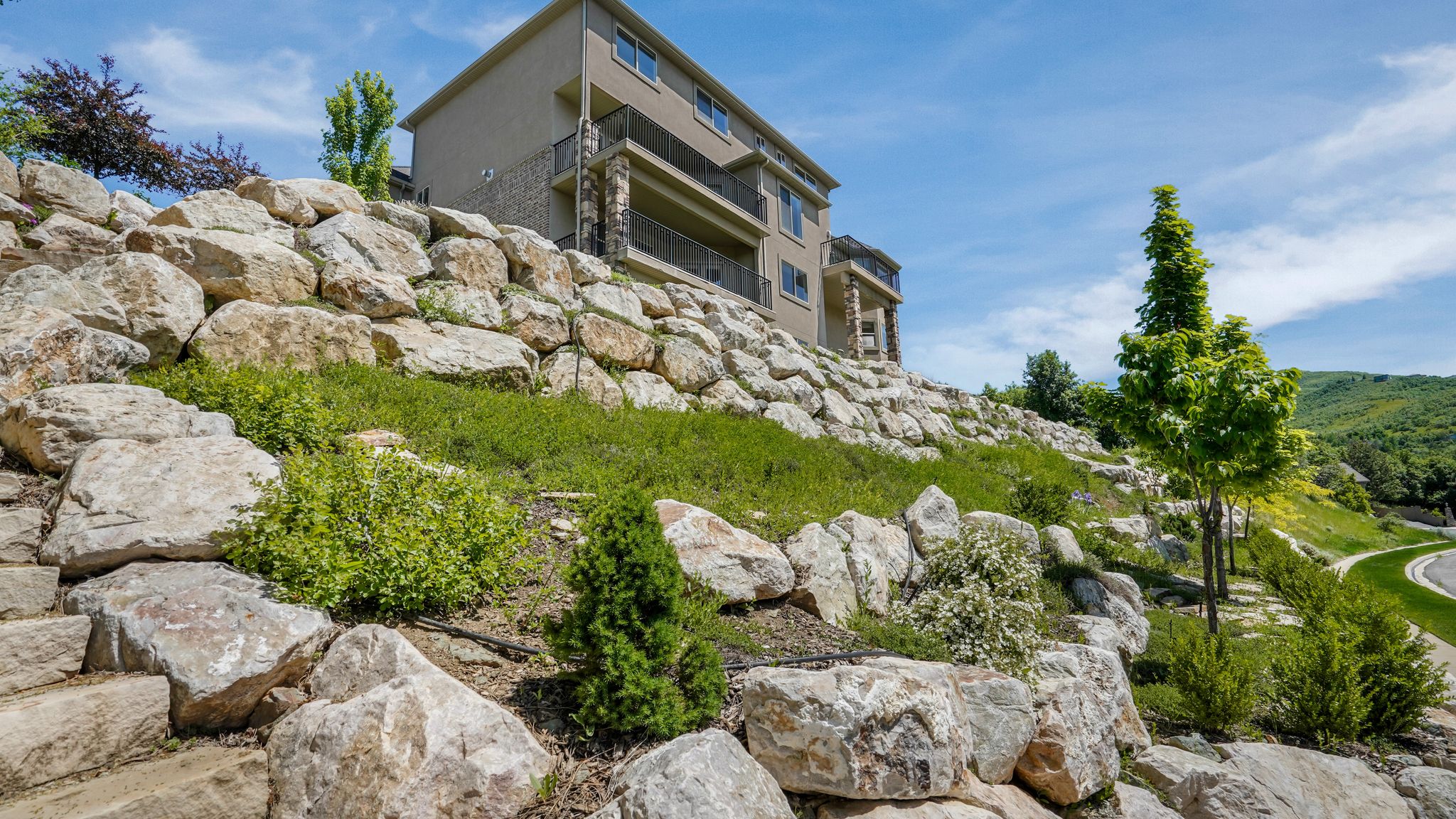 Terraced landscaping featuring large natural rock retaining walls and varied plantings