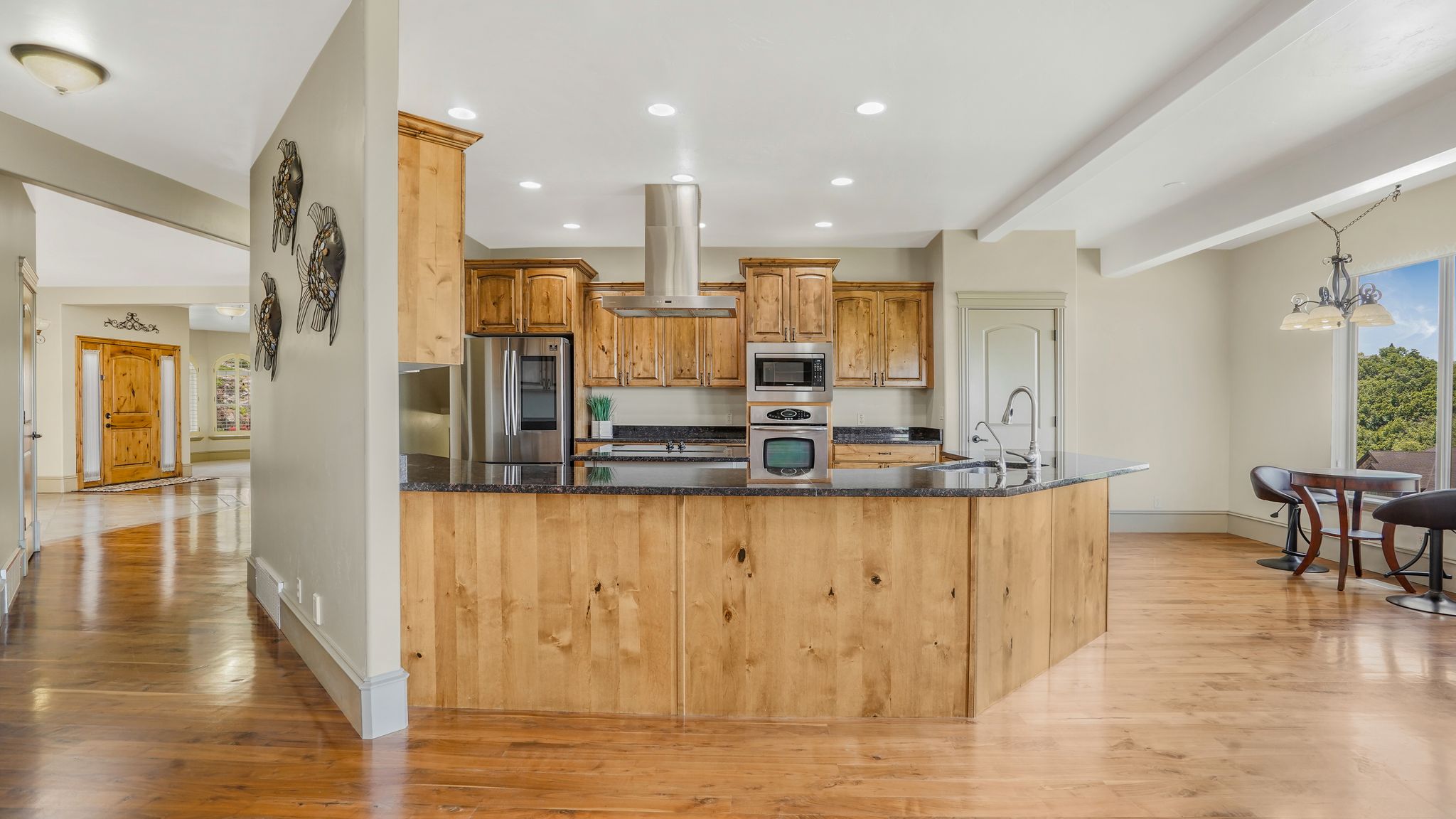 Kitchen featuring wood-finish cabinetry, black stone countertops, stainless steel appliances, and a central island with a sink