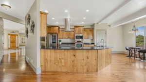 Kitchen featuring wood-finish cabinetry, black stone countertops, stainless steel appliances, and a central island with a sink