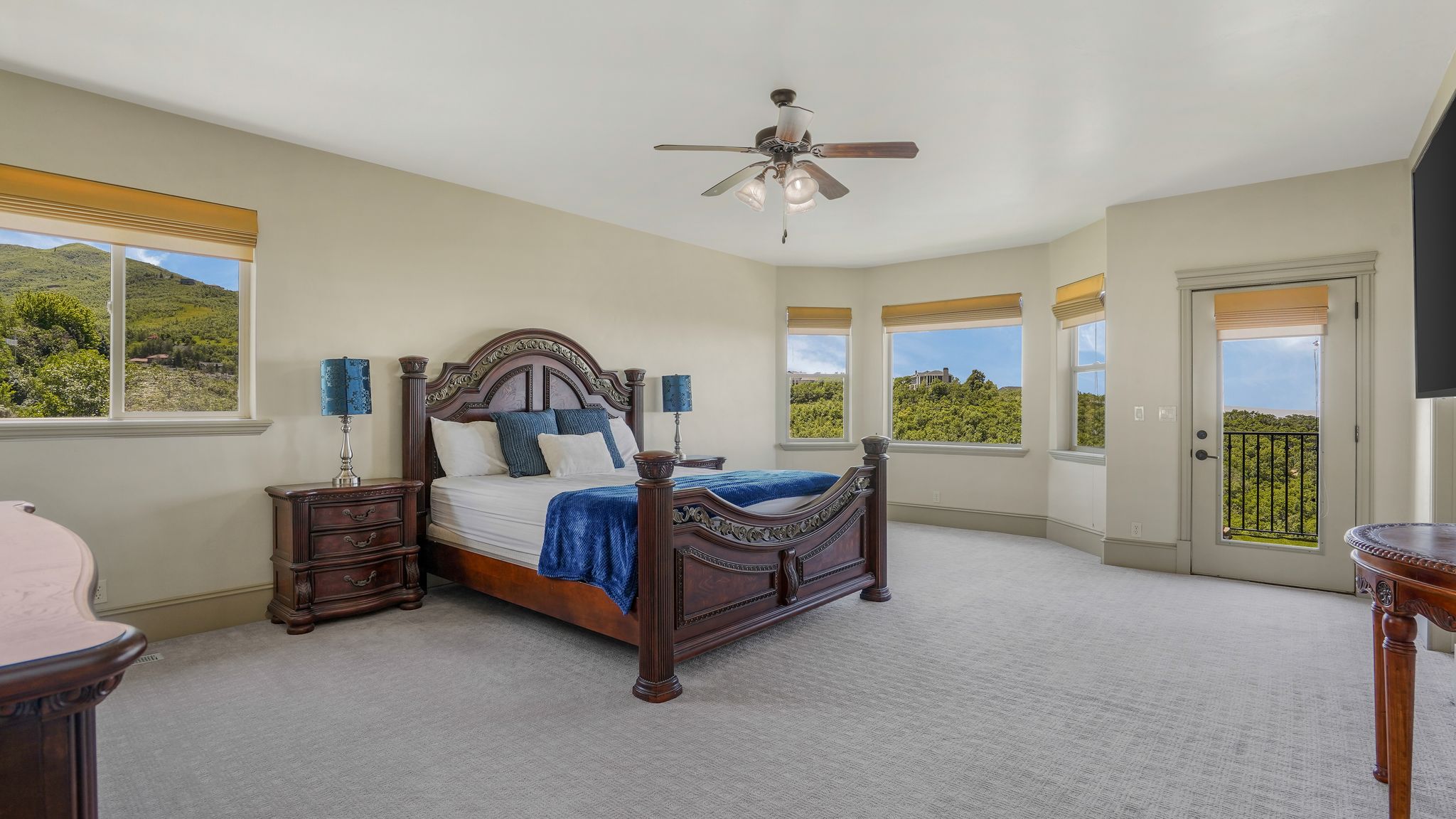 Spacious room featuring light-colored walls, patterned carpeting, and a ceiling fan