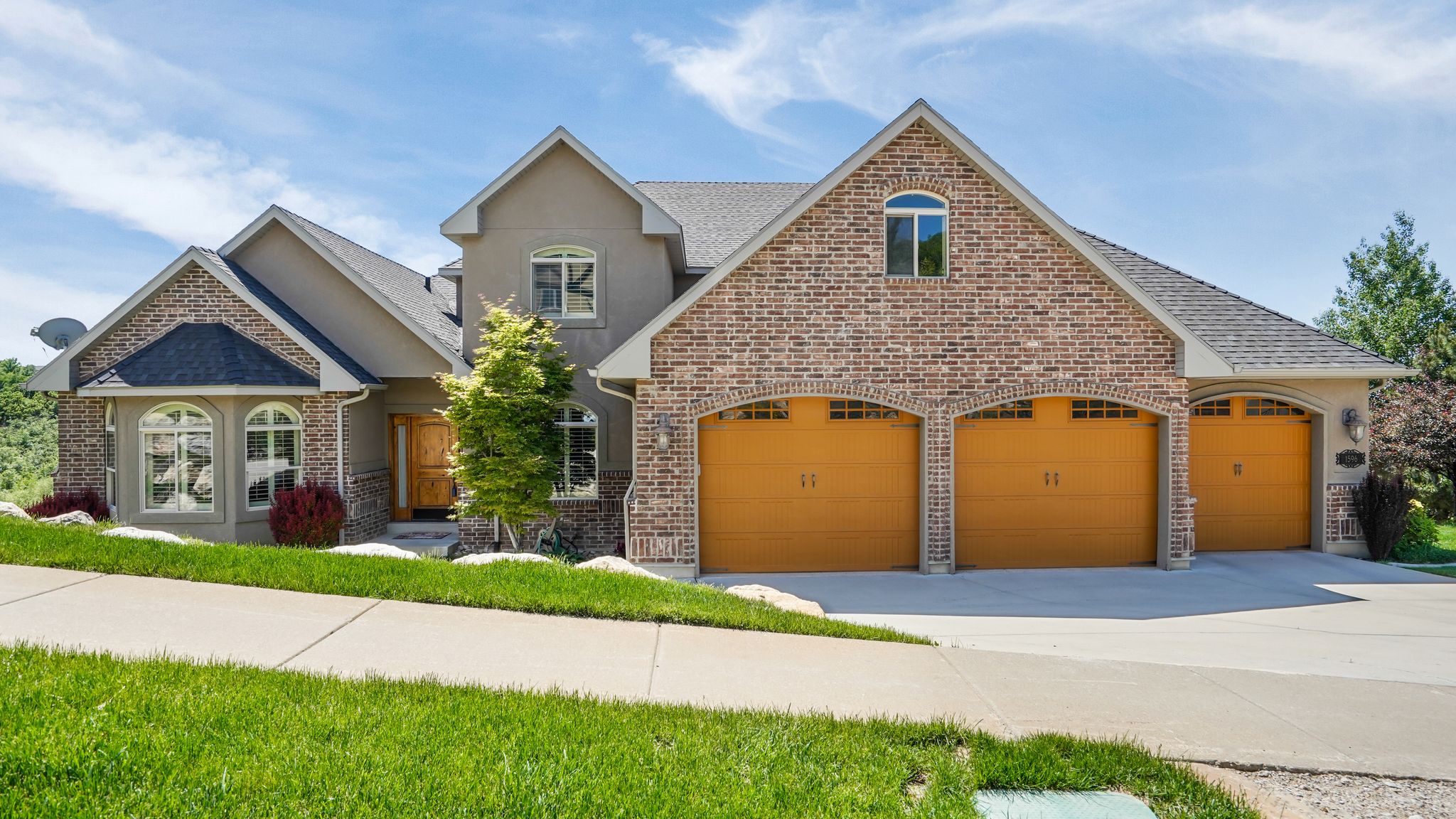Stucco and brick facade with arched entryway over the three-car garage