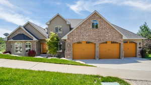 Stucco and brick facade with arched entryway over the three-car garage