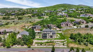 Elevated hillside residence featuring a multi-level design with stone retaining walls, extensive landscaping, and a broad upper-level balcony