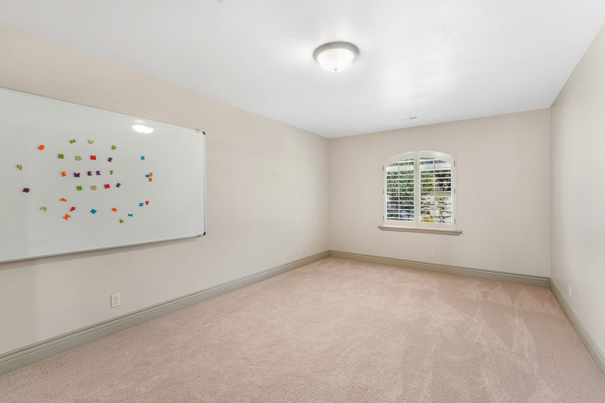 Neutral tone walls with an arched window featuring plantation shutters