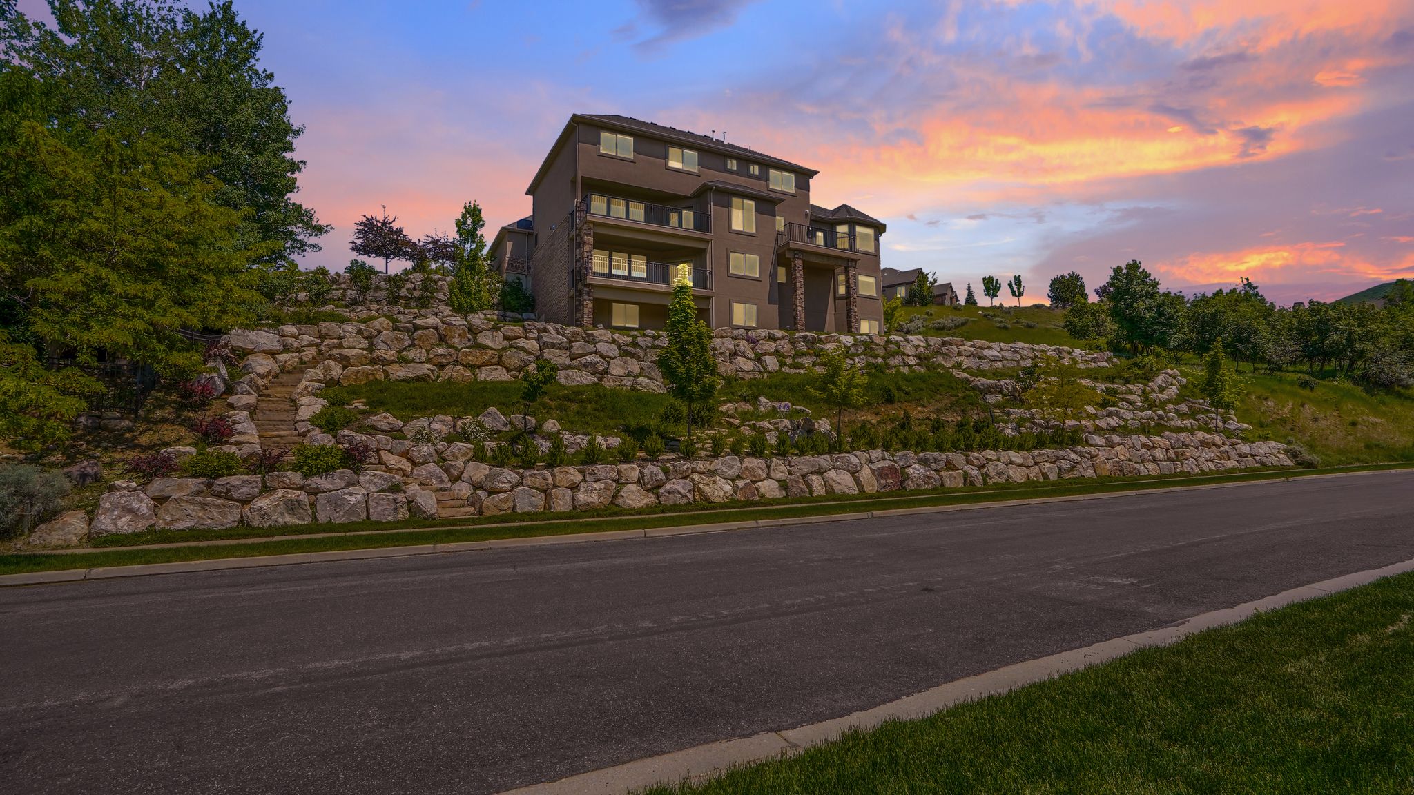Multi-level residence featuring a tiered natural stone retaining wall and mature landscaping
