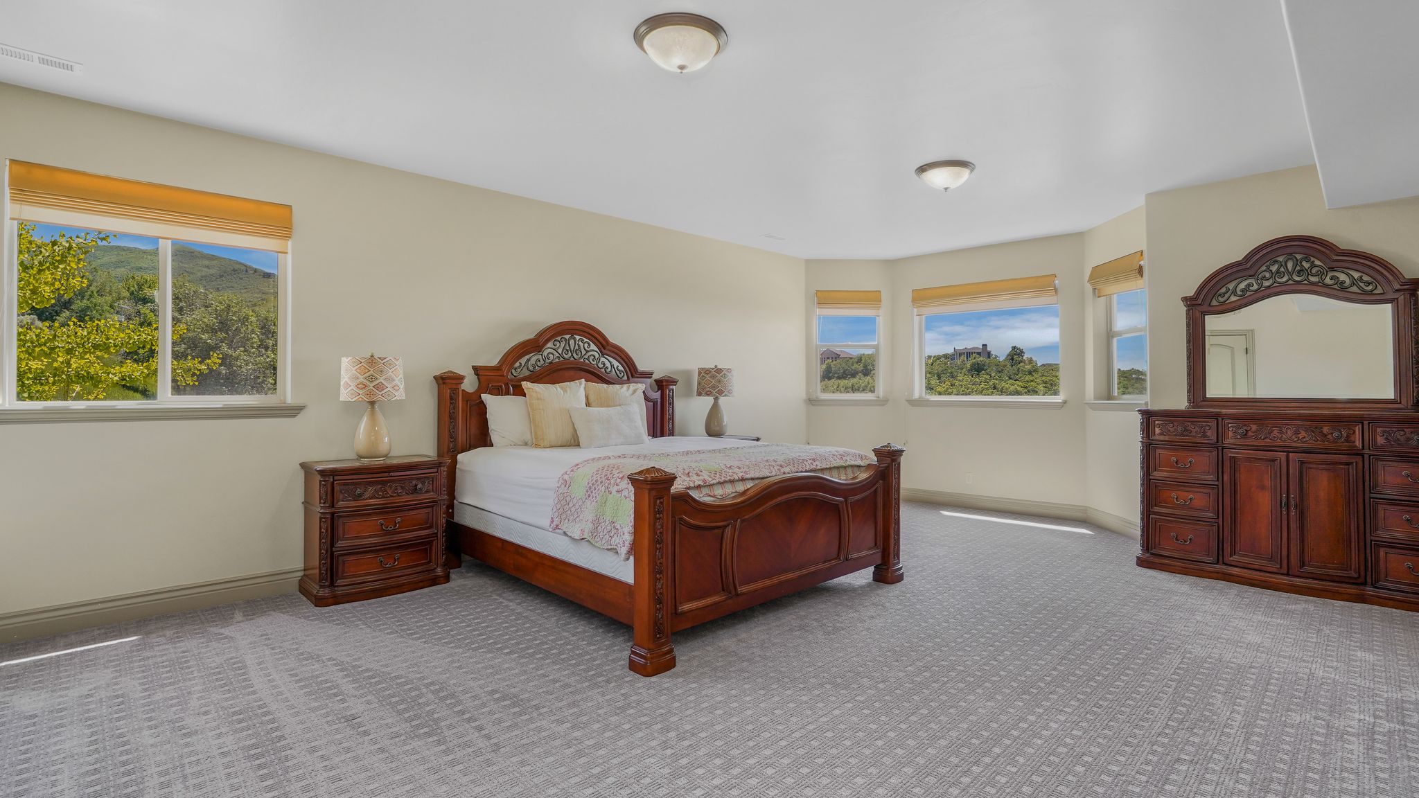 Spacious room featuring patterned gray carpeting, multiple windows, and light beige walls