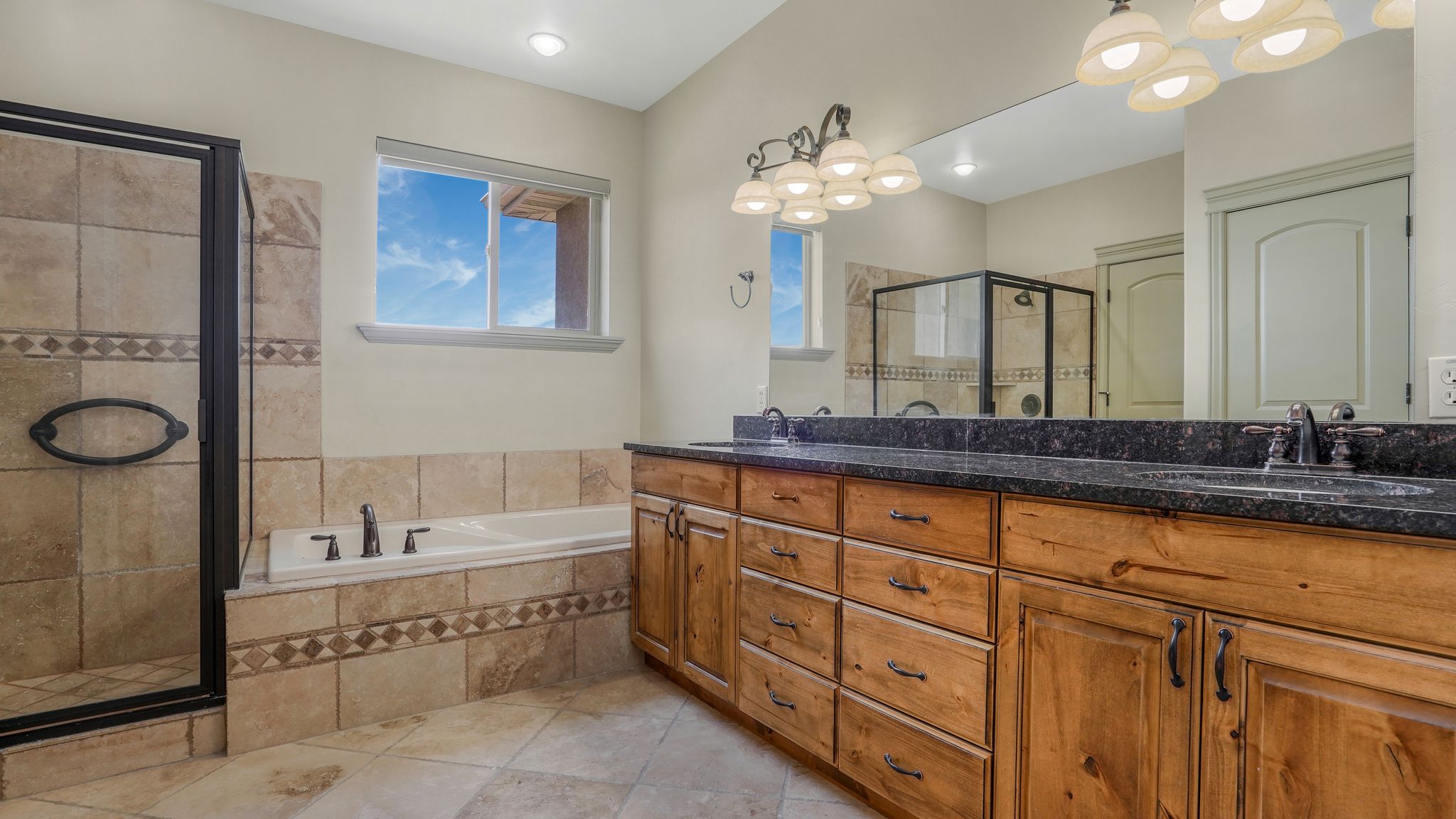 Dual vanity with wood-finish cabinetry and dark stone countertops