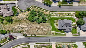 Aerial perspective showcasing a residential property with a multi-gabled dark gray roof, a concrete driveway, and surrounding green lawns