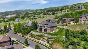Multi-story residence featuring a brick and stucco exterior, tiered landscaping with stone retaining walls, and a multi-level deck