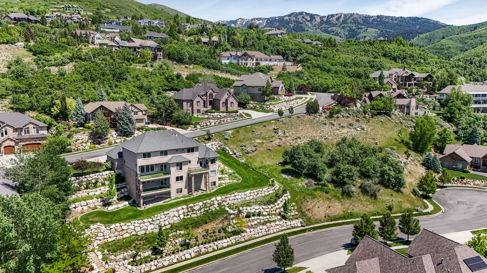 Terraced landscaping with stone retaining walls, mature trees, and manicured lawn