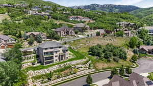 Terraced landscaping with stone retaining walls, mature trees, and manicured lawn