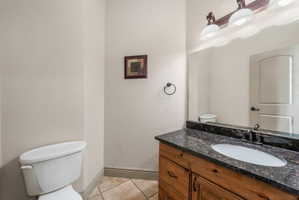 Bathroom featuring a vanity with a dark countertop, an oval undermount sink, and a dark bronze faucet