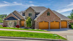 Multi-level residence featuring a brick and stucco exterior, a prominent three-car garage with arched entrances, and a gabled roofline