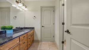 Double vanity with a dark granite countertop, undermount sink, and wood-finish cabinetry