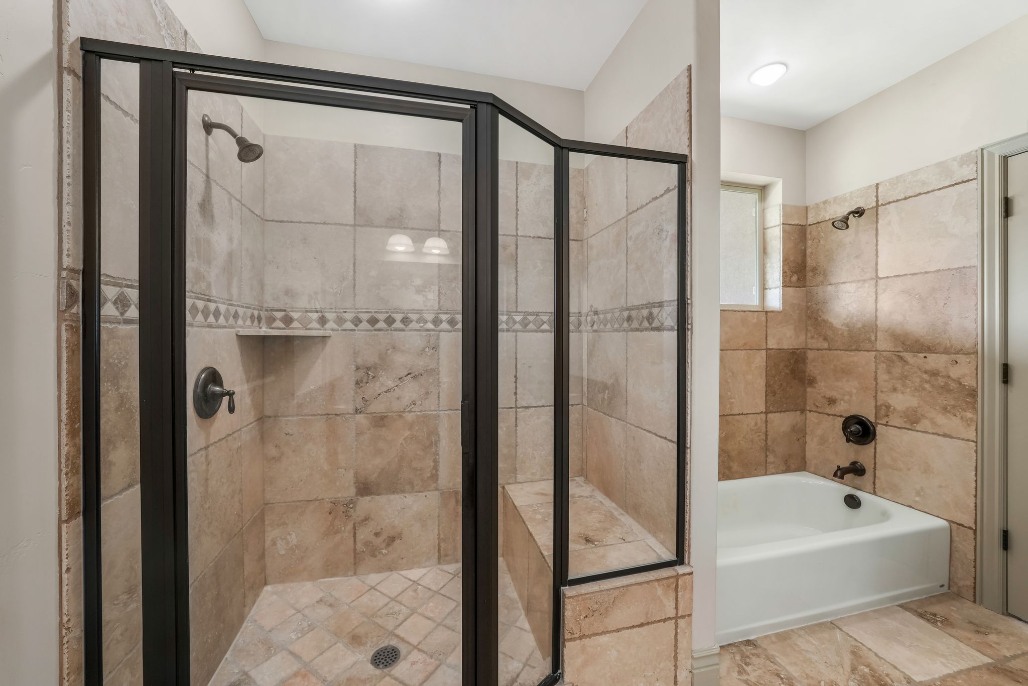 Walk-in shower with dark bronze framing, an integrated shower bench, and an accent tile band