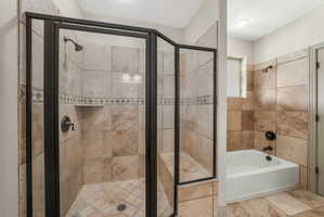 Walk-in shower with dark bronze framing, an integrated shower bench, and an accent tile band