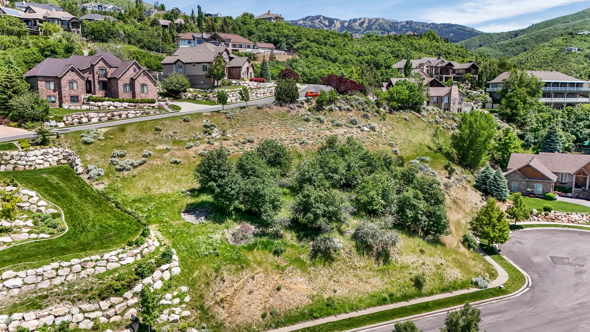 Elevated residential lot featuring terraced landscaping with stone retaining walls and mature trees