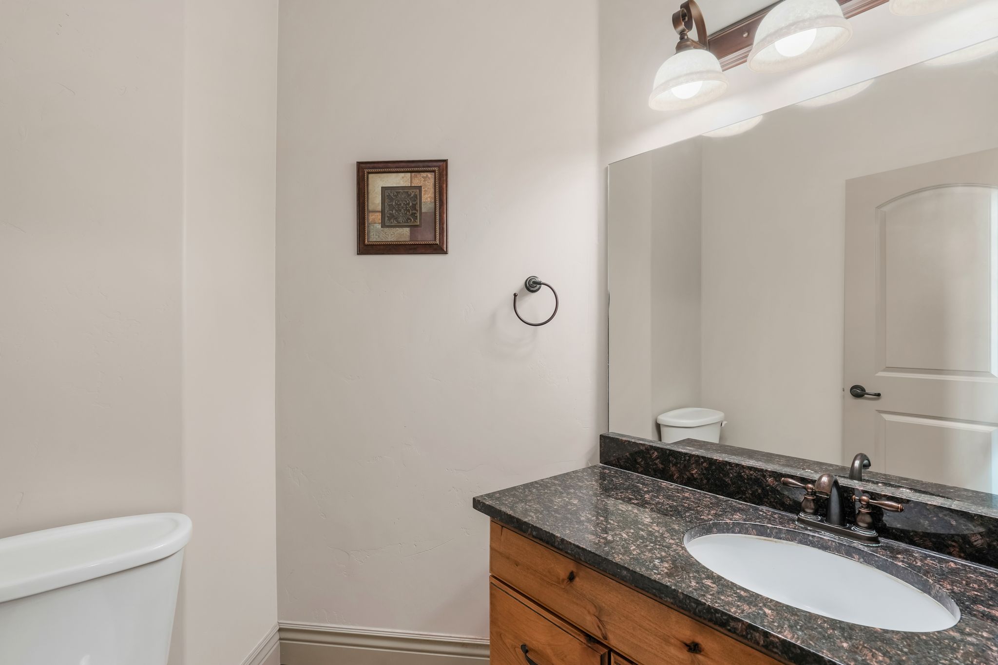 Bathroom vanity featuring a dark granite countertop with an oval undermount sink and oil-rubbed bronze faucet