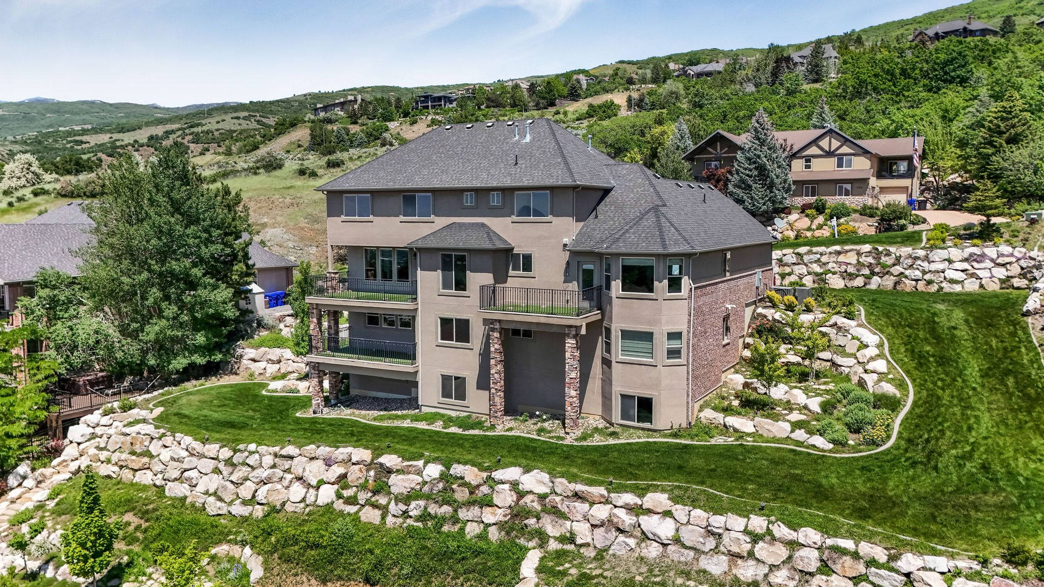 Multi-level residence featuring stucco and brick exterior finishes, a dark shingle roof, and multiple balconies