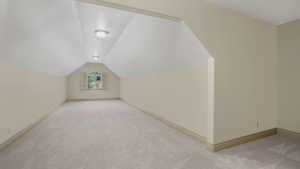 Spacious room featuring vaulted ceilings, plush carpet flooring, recessed wall niche, and natural light from a window with plantation shutters