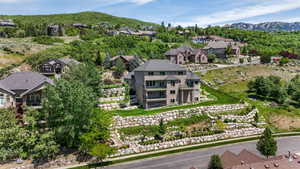 Hillside residence featuring multiple levels of stone retaining walls, terraced landscaping, a prominent balcony, and a multi-story exterior