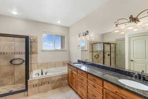 Bathroom featuring a double vanity with stone countertop, dual sinks, and light fixtures