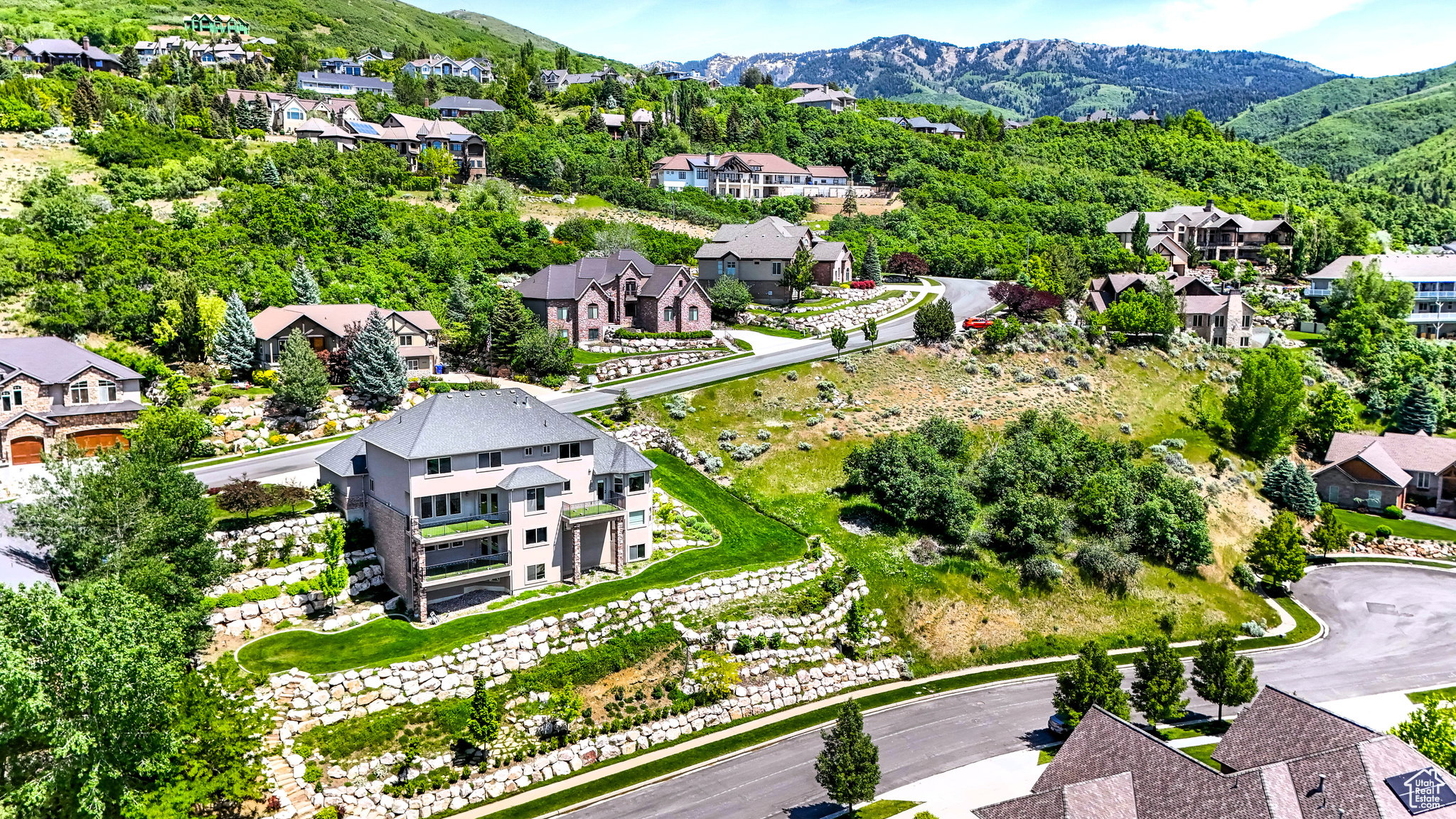 Residential community featuring multiple homes set on a hillside with surrounding mountain terrain