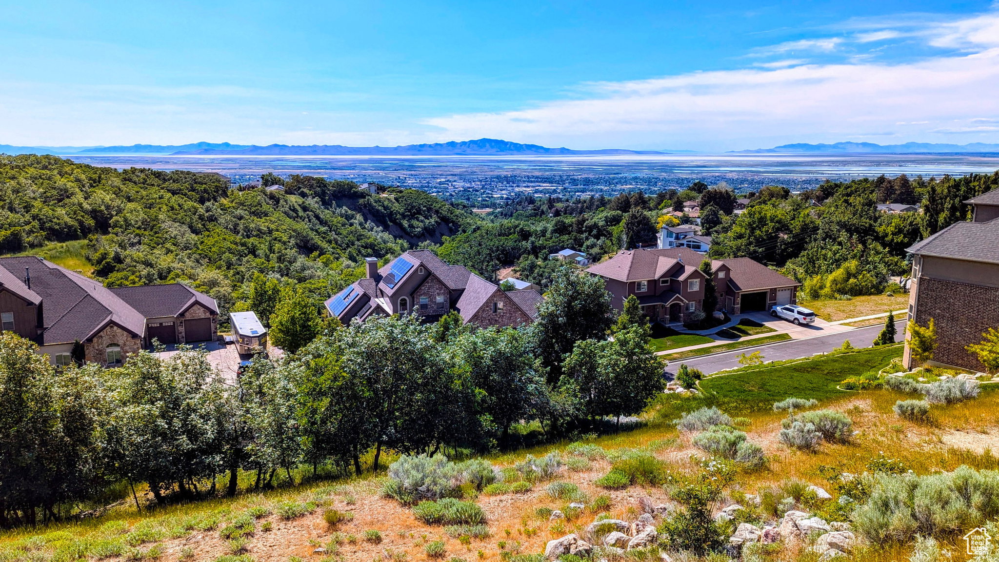 Expansive hillside setting featuring multiple residences with distant city and mountain backdrops
