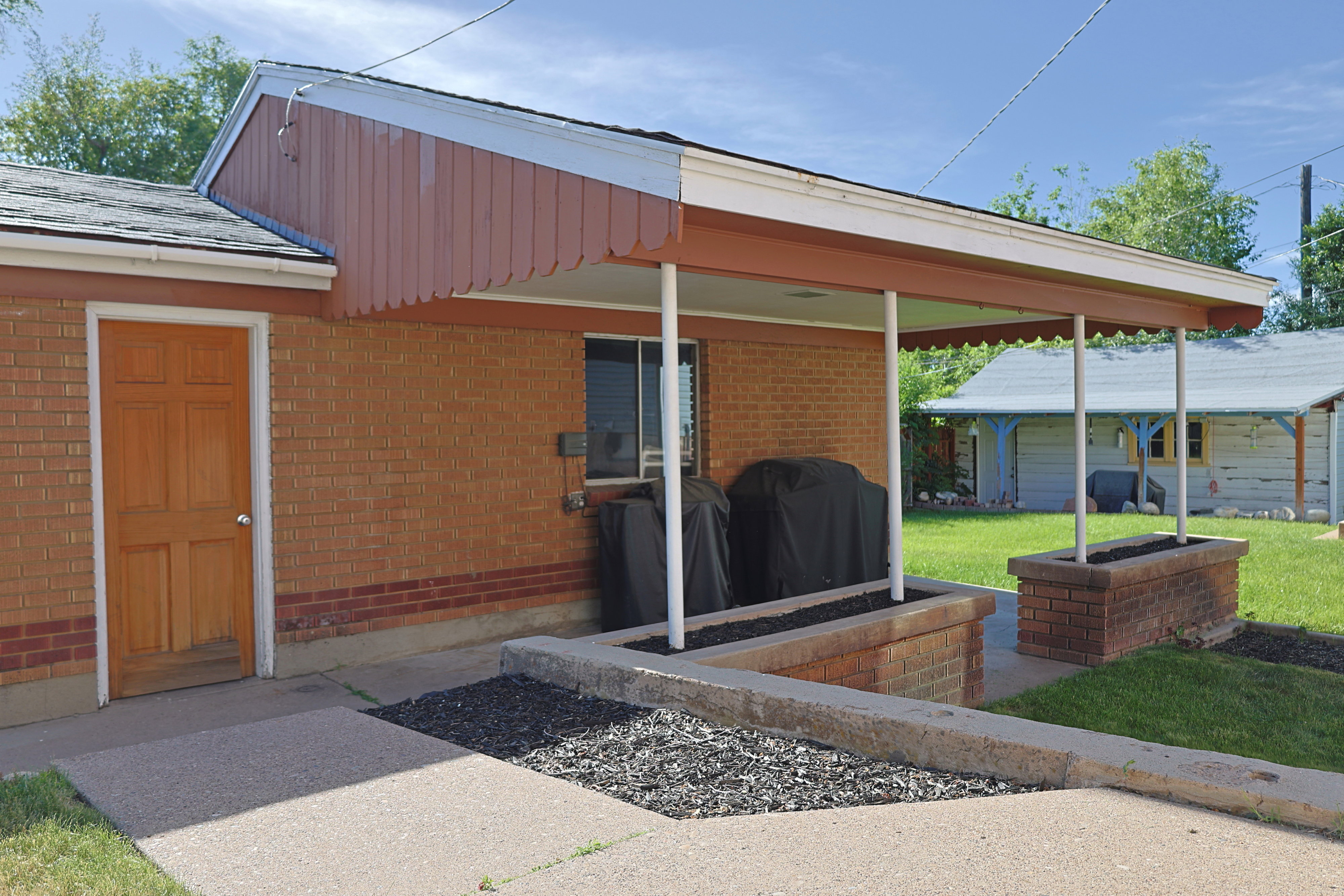 Brick exterior garage with a covered patio featuring a scalloped fascia and support columns