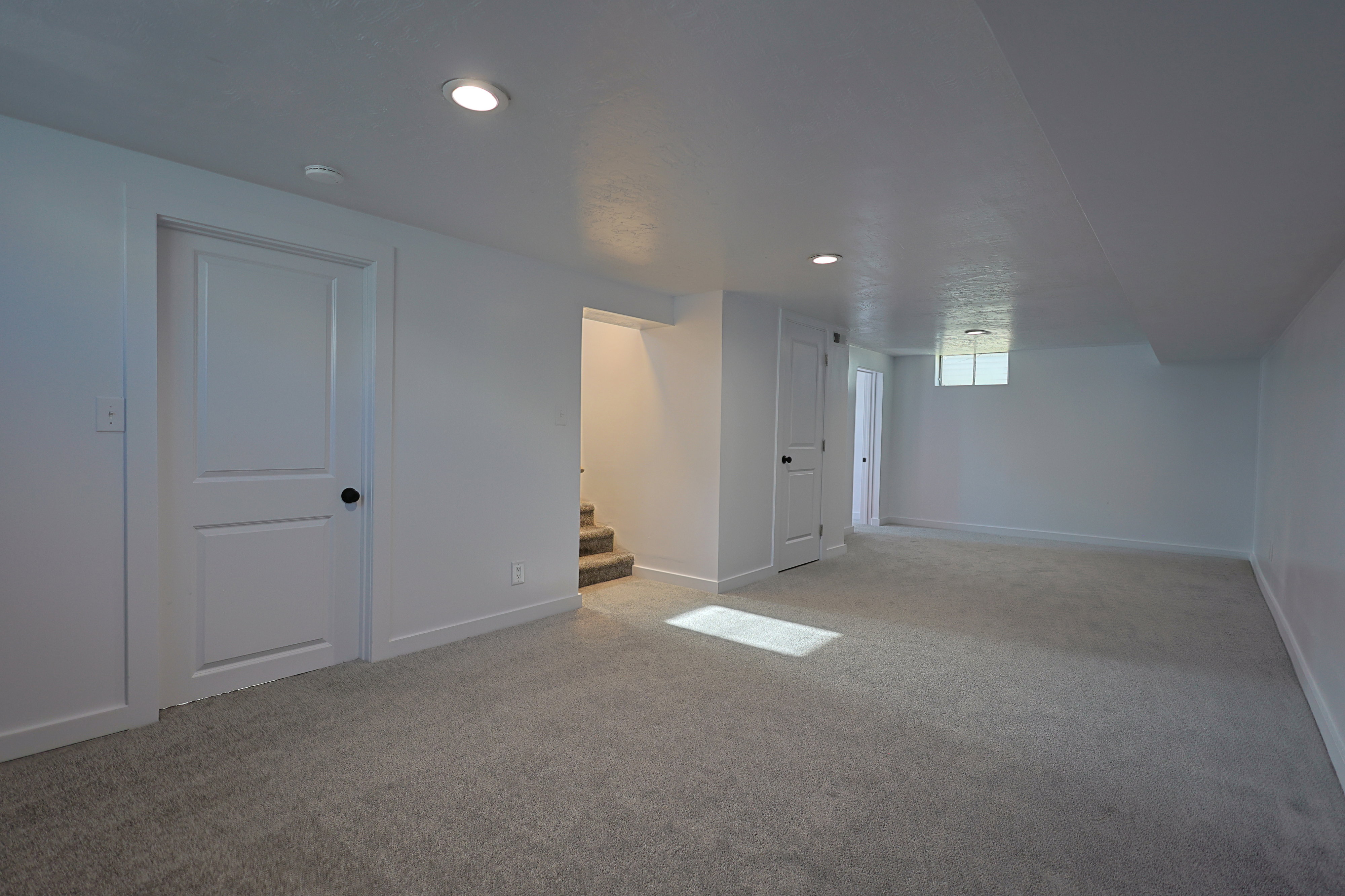 Spacious family room featuring light-colored carpeting, recessed lighting, and white walls