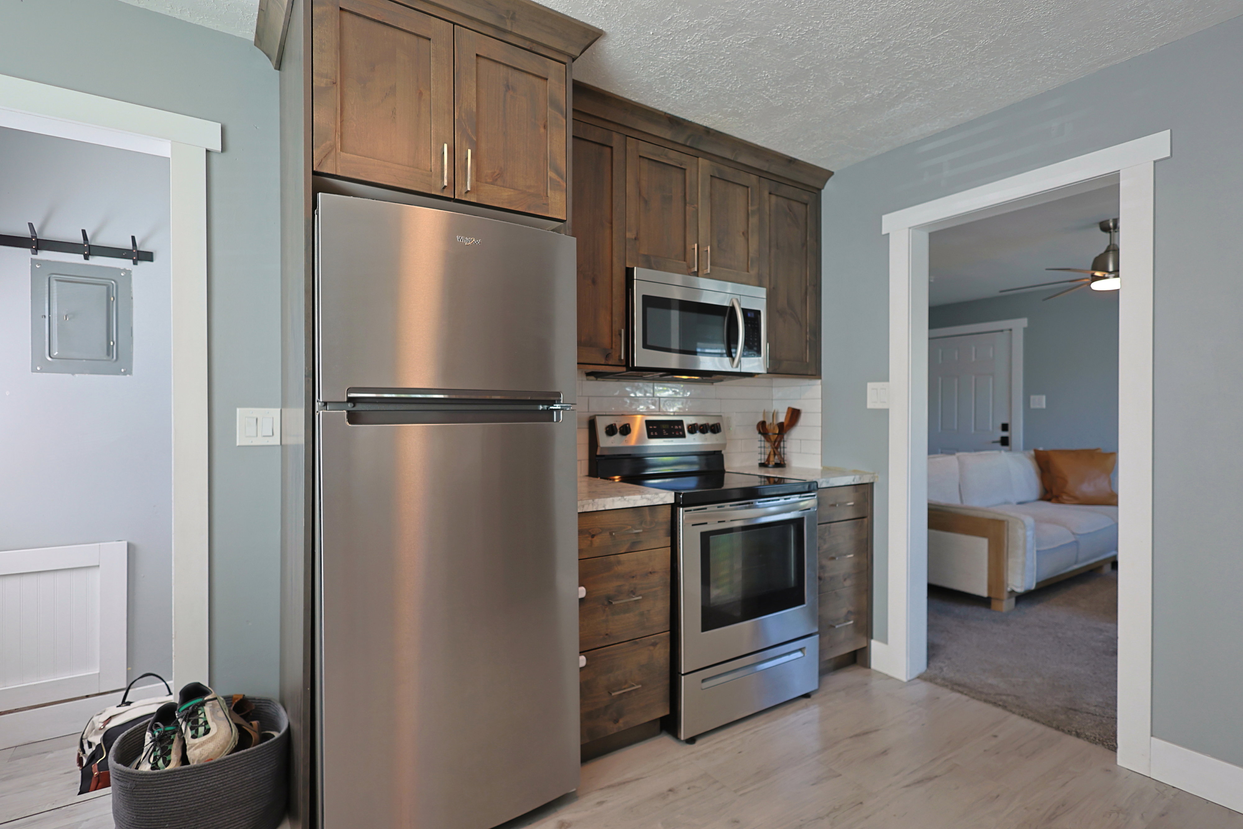 Kitchen featuring wood-finish cabinetry, stainless steel appliances, light-toned countertops, and a white subway tile backsplash