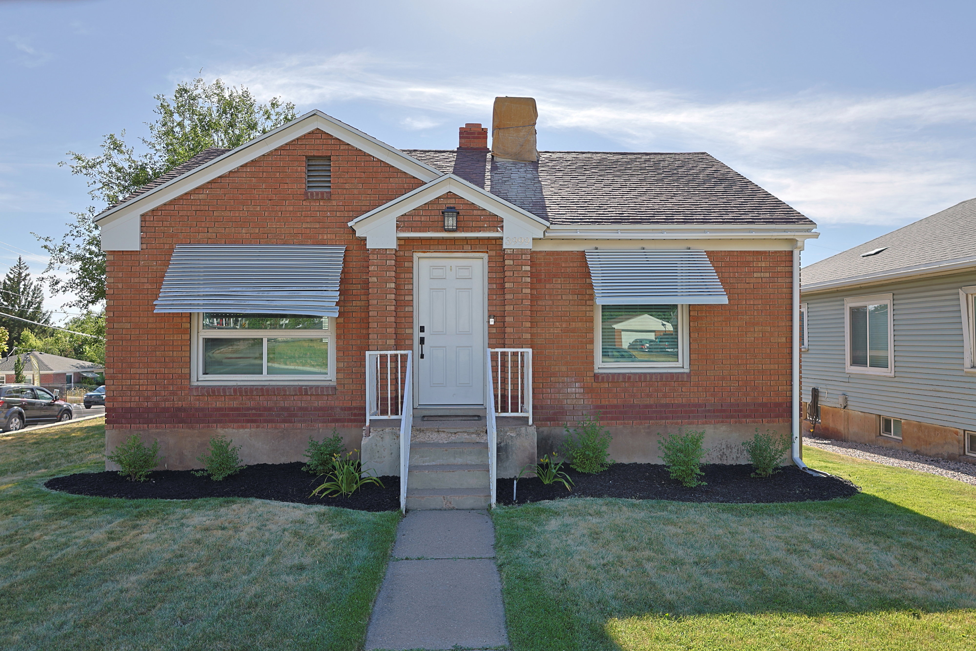 Brick exterior with a white entry door, covered porch, and white railings