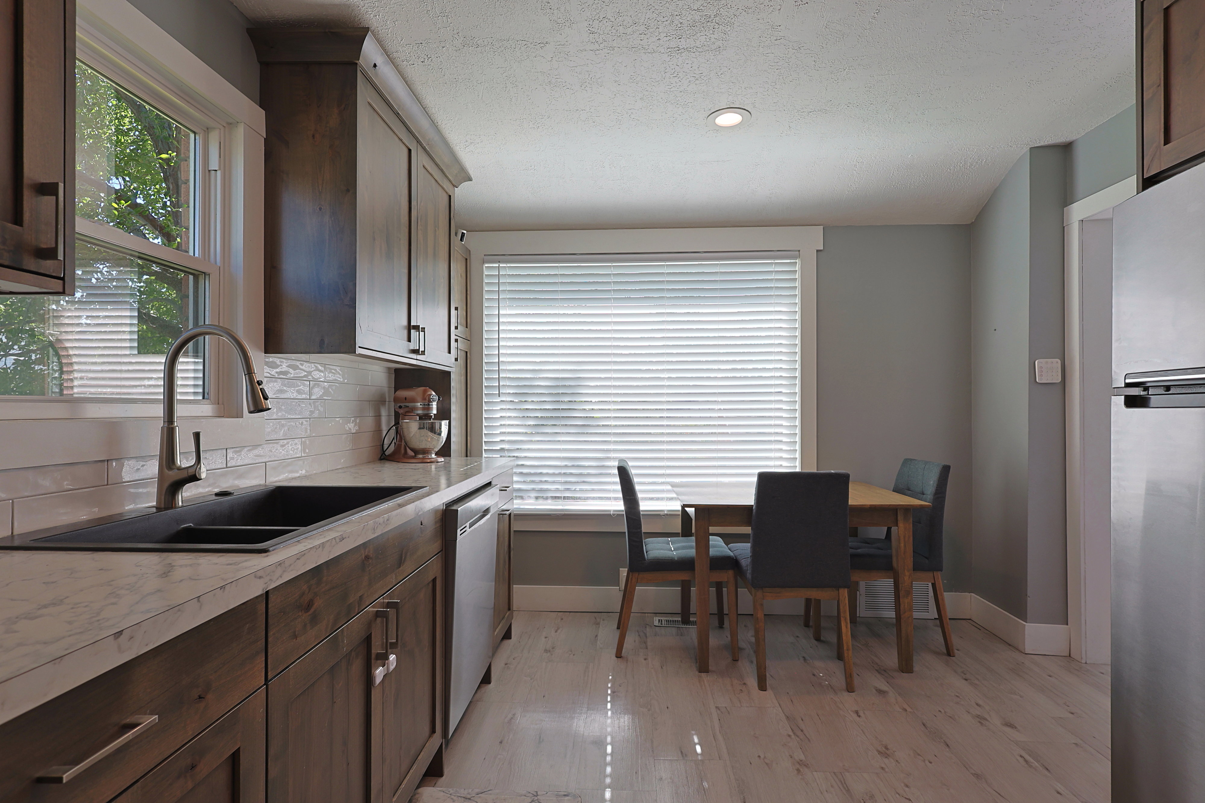Kitchen featuring wood cabinetry, light-toned countertops, a black double-basin sink with a gooseneck faucet, and a subway tile backsplash
